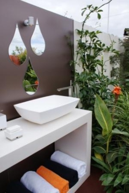 a small modern bathroom nook with a floating vanity, a sink and drop-shaped mirrors