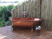 a vintage-inspired outdoor bathroom nook with a copper tub and a wrought side table