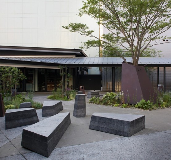 a minimalist outdoor space done with a tree and some concrete stools and benches for a very laconic and edgy look