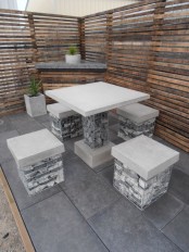 a modern rustic outdoor space with a corner table, a concrete table and stools filled with pebbles is an unusual and bold idea
