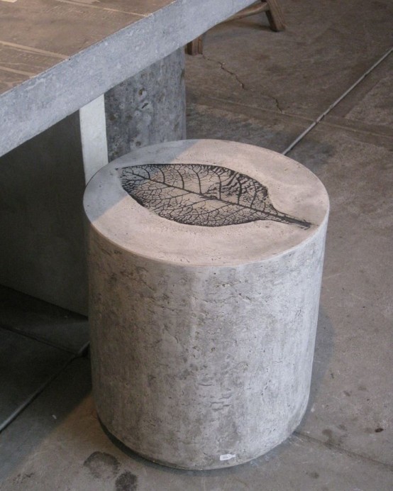 a concrete dining table paired with a concrete stool with a leaf print are a lovely combo for a modern or minimalist terrace