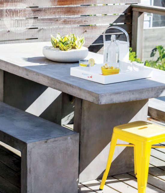 a stylish terrace with reclaimed wood and a concrete table and benches, a bold yellow stool for a touch of color