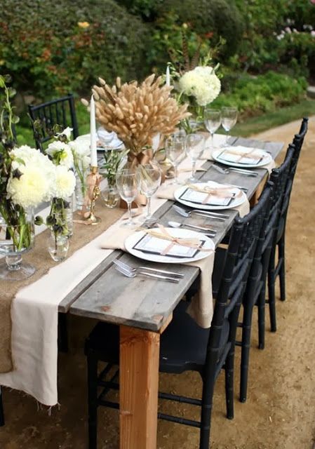 a cozy and neutral Thanksgiving with a burlap runner, a wheat centerpiece, neutral blooms and candles in gold candleholders