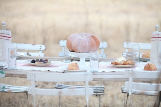 a white Thanksgiving tablescape with neutral pumpkins, a striped runner, striped plates