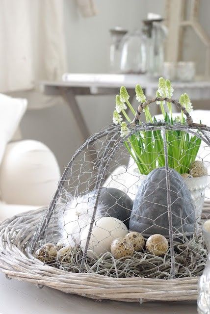 Easter Scandinavian decor with a vine tray, hay and eggs   natural and fake ones, feathers and bulbs in a pot