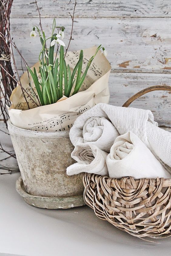 simple Nordic spring decor with a concrete planter with bulbs and twigs plus note paper and a basket with neutral towels