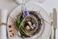 a Scandinavian place setting with fake nests, eggs and bulbs, an egg candle and some neutral linens
