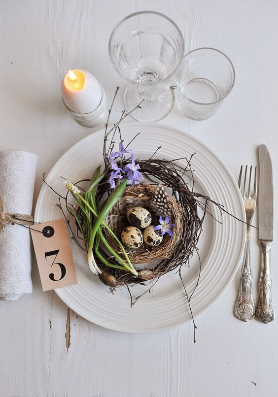 a Scandinavian place setting with fake nests, eggs and bulbs, an egg candle and some neutral linens