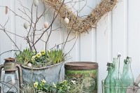 shabby chic Scandinavian decor with buckets and boxes with greenery and pansies, branches with eggs and a hay heart-shaped wreath