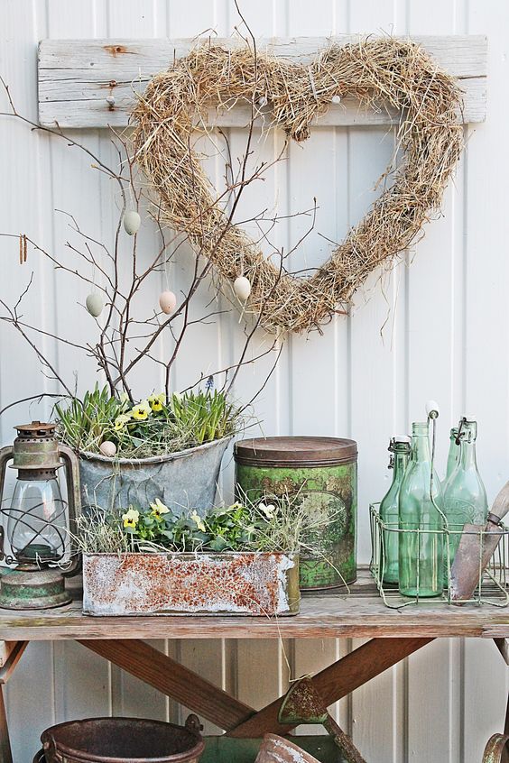 shabby chic Scandinavian decor with buckets and boxes with greenery and pansies, branches with eggs and a hay heart shaped wreath