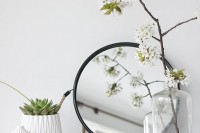 a white pot with a succulent, a white vase and a sheer one with blooming branches for a spring touch to your space