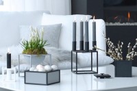 a laconic Nordic composition with a box with fake eggs, metal frame candleholders, a box with willow and a framed planter with bulbs