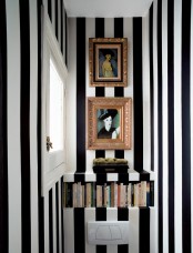 a small striped black and white guest toilet with some artworks and books