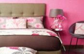 a pink bedroom with a taupe upholstered bed, floral bedding, a small nightstand and a taupe chair is a lovely space
