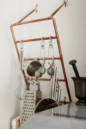 a copper pipe holder with lots of stuff is a lovely and cool idea for any space, it can be used not only in an industrial kitchen