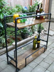 a home bar of black pipes and stained wood can be placed both indoors and outdoors as these materials are very durable