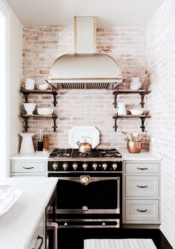 a vintage dove grey kitchen with shaker style cabinets, a vintage cooker, a vintage hood and open shelves plus a whitewashed brick backsplash
