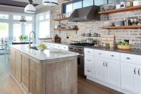 a pretty kitchen with white shaker style cabinets, grey countertops, a brick backsplash, a rough wooden kitchen island and a white countertop is a chic and stylish idea