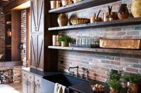 a vintage rustic dark-stained kitchen with rough wooden cabinets, black countertops, open shelves, a red brick backsplash and vintage appliances is amazing