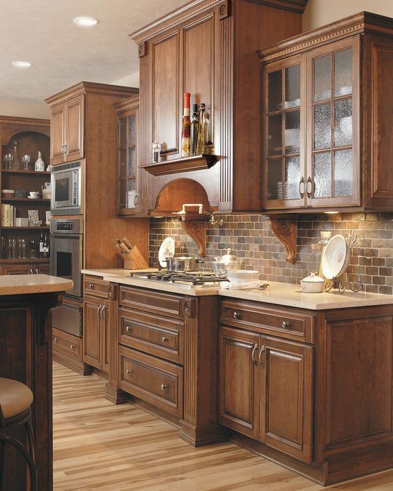 a vintage dark stained kitchen with shaker style cabinets, white countertops, a brick backsplash and built in lights looks elegant, chic and stylish