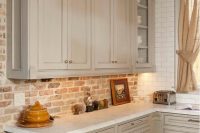 an elegant dove grey kitchen with shaker style cabinets, white countertops, a red brick backsplash, neutral curtains is a lovely idea for an eclectic home