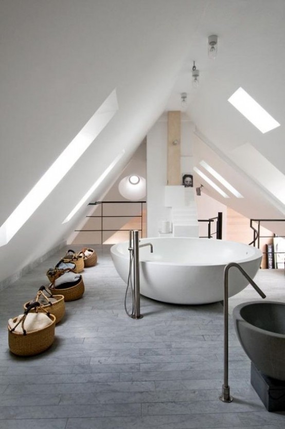 a contemporary attic bathroom with a grey tile floor, a large round tub and some baskets for storage