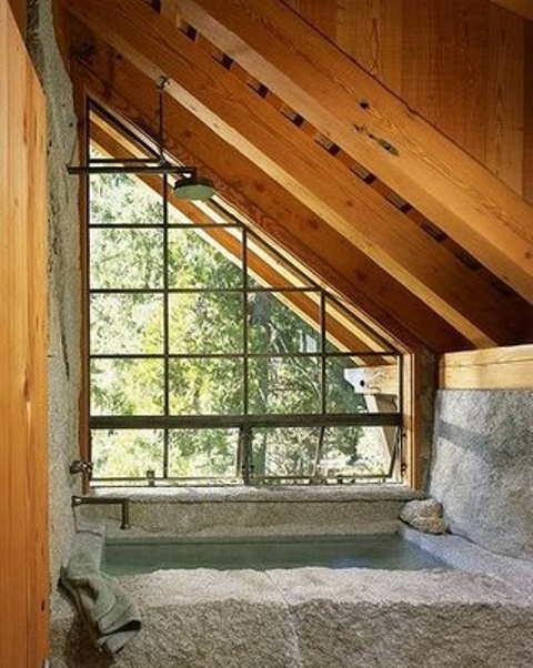 an attic stone and wood bathroom with a bathtub for relaxation and a wooden ceiling