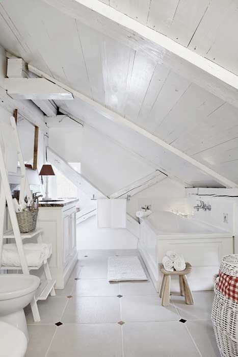 a pure white attic bathroom with a vintage feel, whitewashed wood, a tub, a ladder for storage and a sink in white