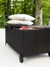 a black mobile bench withh storage space inside is a cool idea for a small balcony