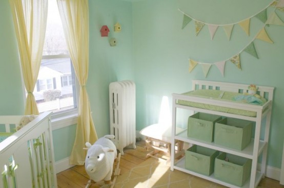 a small mint-colored nursery with white furniture, yellow curtains, buntings and toys, baskets and boxes is a great space