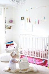 a neutral nursery spruced up with bold colors, with modern white furniture, colorful textiles and toys is a pretty and lovely kid’s space