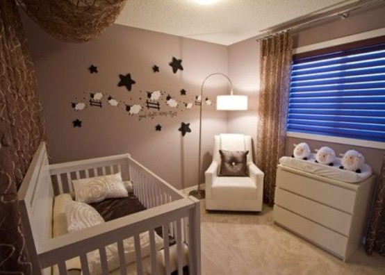 a tiny taupe nursery with a white crib, a white chair and dresser, a funny gallery wall and some lights