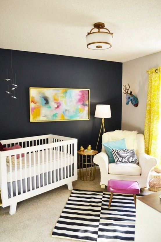a bright mid-century modern nursery with a black accent wall, white furniture, layered rugs, a bright artwork and some pillows, a pink pouf