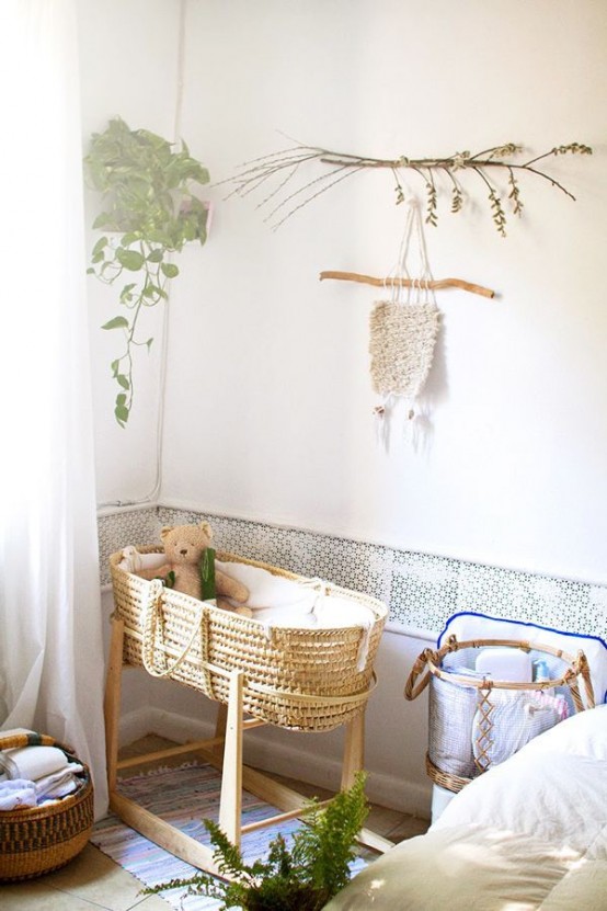 a tiny nursery with a little basket-style crib, a sofa, a basket for textiles, greenery and branches is amazing for a boho home