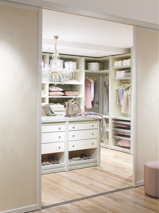 a lovely pastel feminine closet done in pastel green and pink, with a crystal chandelier and a large storage unit with drawers and an open storage unit