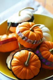 decorate pumpkins with colorful stripes of paper and fabric to create a bright and natural fall centerpiece