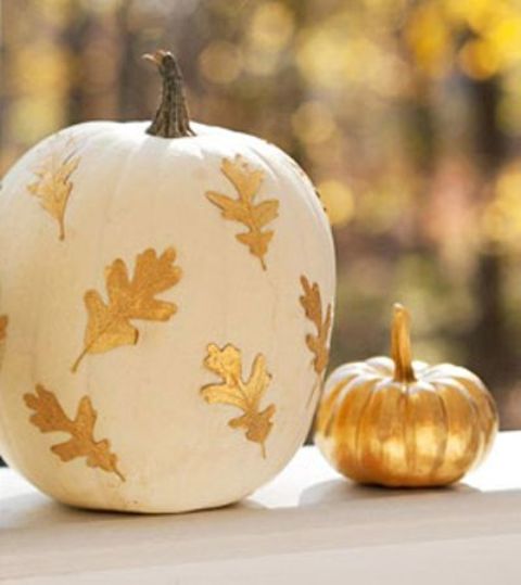 a pumpkin painted gold and a white pumpkin with gold leaves on it are cool and chic fall decorations