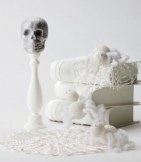 refined white Halloween decor with doilies, vintage books, yarn balls and a skull on a stand is a beautiful idea
