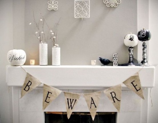 a white Halloween mantel with a burlap bunting, black and white pumpkins, white vases with branches with cotton buds is chic and out-of-the-box