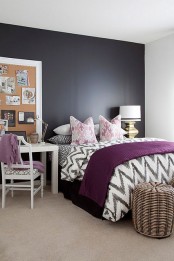 a black and white bedroom with a black bed, woven baskets for storage, white furniture, a board for memos and table lamps