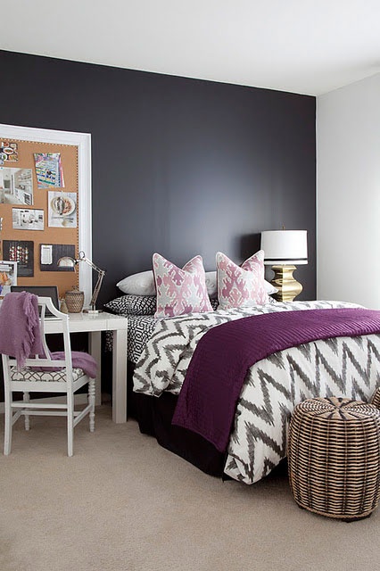 a black and white bedroom with a black bed, woven baskets for storage, white furniture, a board for memos and table lamps