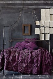 a moody bedroom with chalkboard walls, a forged bed, deep purple bedding and pages of the book attached right to the wall