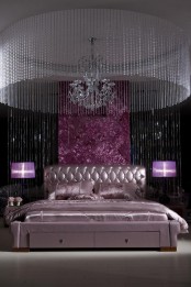 a unique sophisticated bedroom in black and purple, with a metallic lavender bed, a large crystal chandelier, a crystal hanging over bed is just jaw-dropping