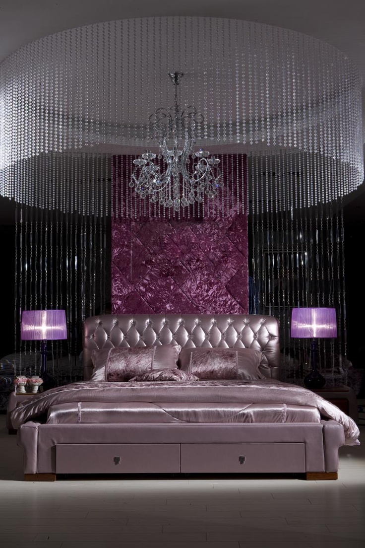 a unique sophisticated bedroom in black and purple, with a metallic lavender bed, a large crystal chandelier, a crystal hanging over bed is just jaw dropping