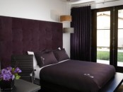 a contrasting deep purple and white bedroom with an upholstered headboard and deep purple textiles plus dark stained furniture is very elegant and laconic