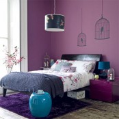 a purple bedroom with cage decals, a black bed, a purple nightstand, a bold butterfly lamp and some bright blue touches
