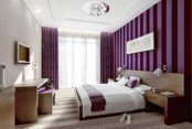 a purple and white bedroom with a striped purple wall and curtains, wooden furniture, a TV and a shiny chandelier is a contemporary bedroom