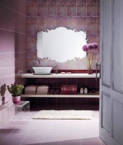 a whimsy purple bathroom with printed tiles, a chic cutout mirror, a floating vanity of shelves and an acrylic table