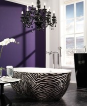 an exotic purple bathroom with a statement wall, a zebra print bathtub, a refined black chandelier and a black free-standing sink