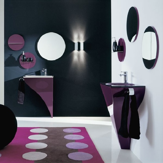 a minimalist black, white and purple bathroom with round mirrors and shelves, purple sinks and a printed rug